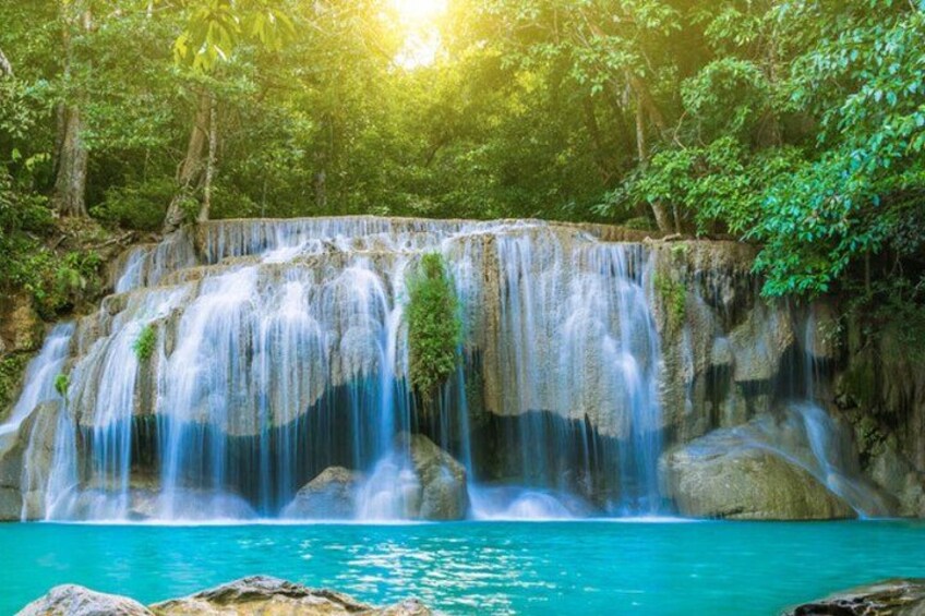 A waterfall cascading over rocks into a turquoise pool surrounded by lush greenery. 3