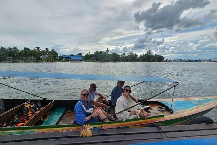 A group of people on a boat with a calm river and a cloudy sky in the background. 5