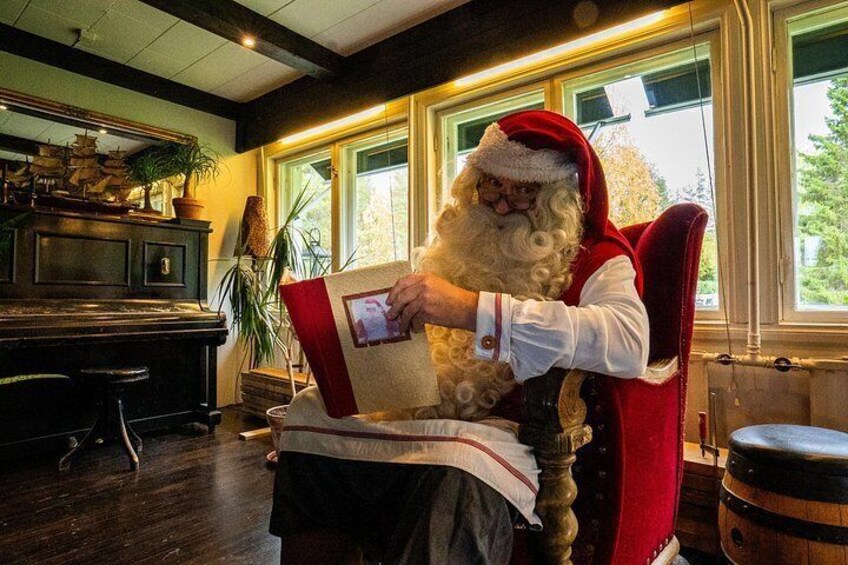 A person in a Santa suit sitting on a red chair, reading a book. 1