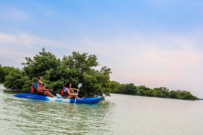 Two people kayaking on a calm river surrounded by dense greenery. 2