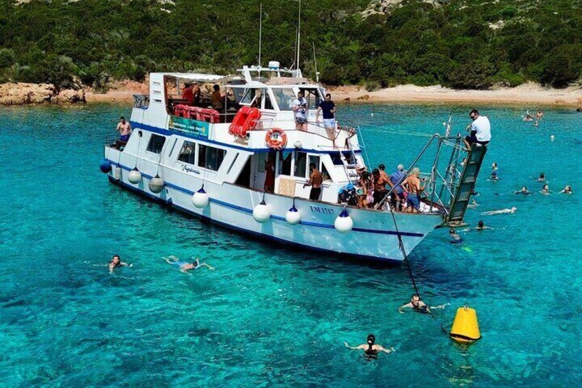 A boat with people swimming and floating around it. 1