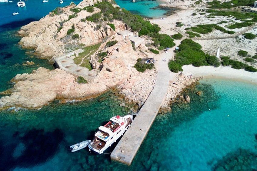 A boat docked at a pier on a rocky island with clear turquoise waters. 5