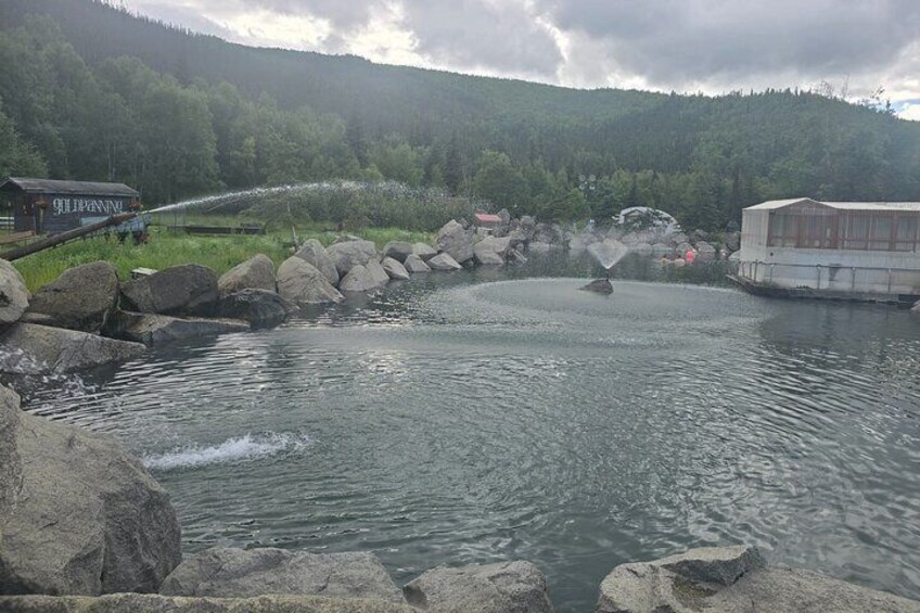 A river with rocks, a boat, and buildings in a forested area. 2