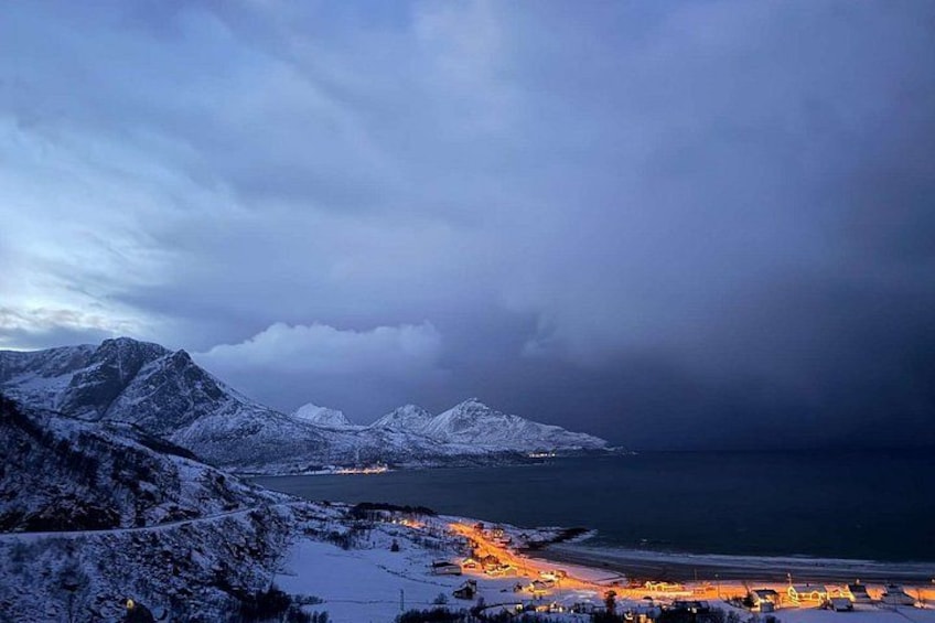 Paesaggio montuoso innevato con una spiaggia e un paese in primo piano. 2