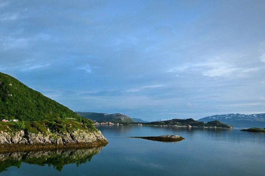 Un lago calmo circondato da dolci colline e montagne lontane sotto un cielo sereno. 3