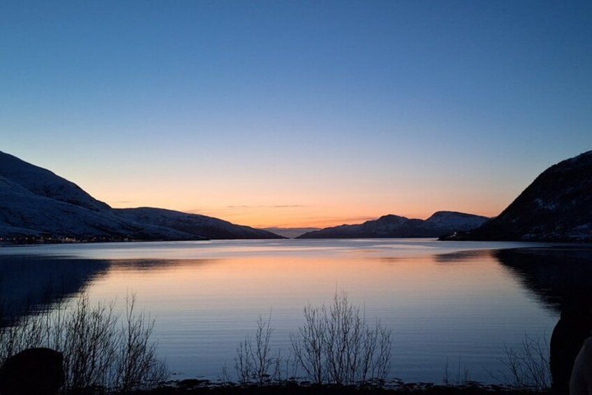 Un lago tranquilo al atardecer con colinas nevadas. 3