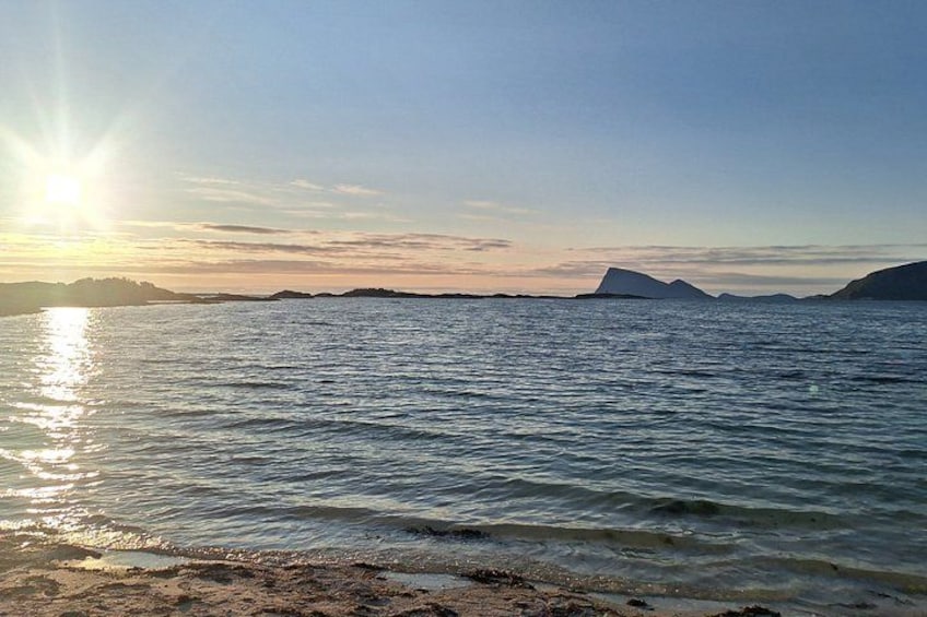 Mare calmo con la luce del sole riflessa sull'acqua, coste lontane e cielo sereno. 4