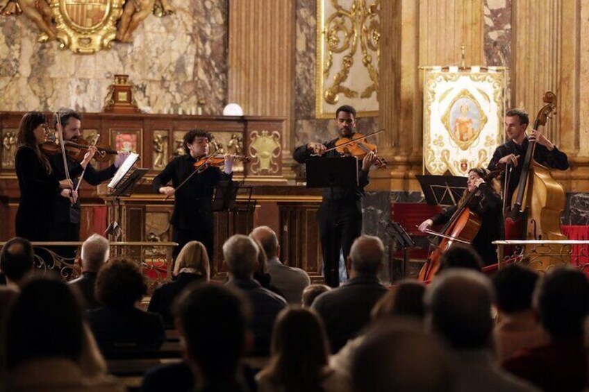 A classical music orchestra performing in a grand hall with ornate decorations and a marble floor. 3