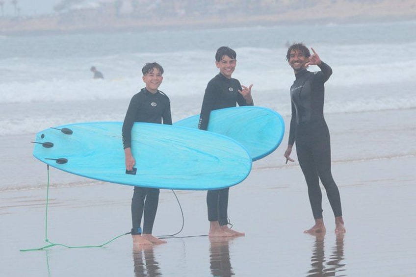 Three people in wetsuits holding surfboards on a beach. 4