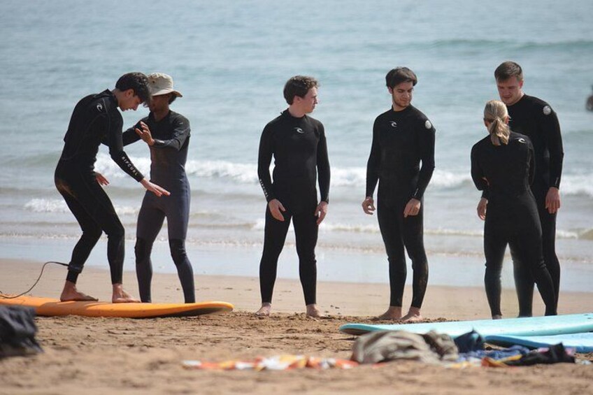 A group of people in wetsuits on a beach with surfboards. 5