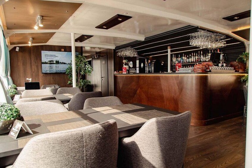 A restaurant with a bar area, wooden ceiling, and cushioned seating. 5