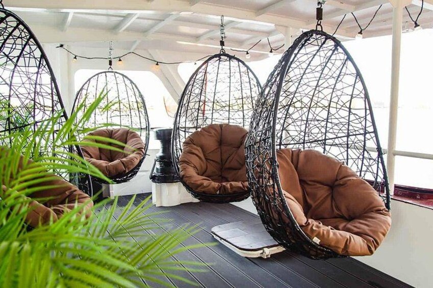 A room with three hanging chairs, a book, and a small table. 3