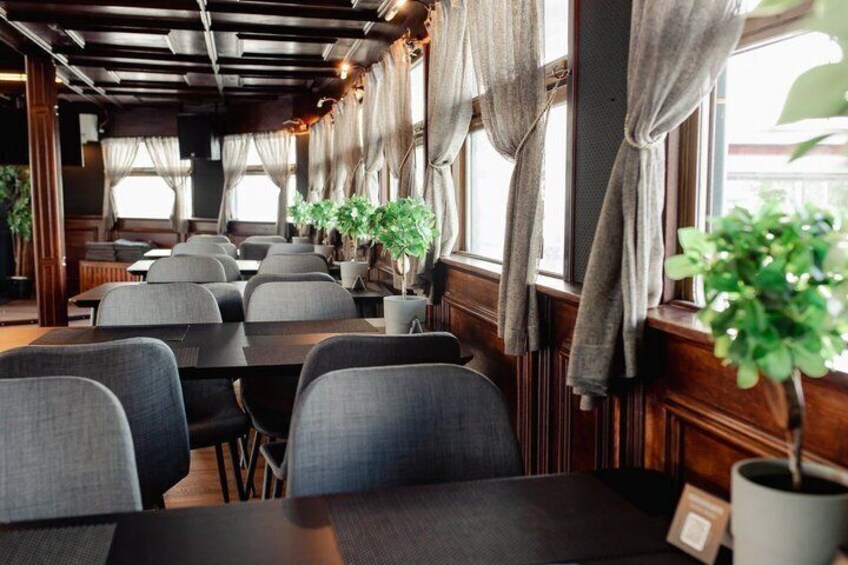 Een restaurantinterieur met houten lambrisering, tafels, stoelen en potplanten. 4