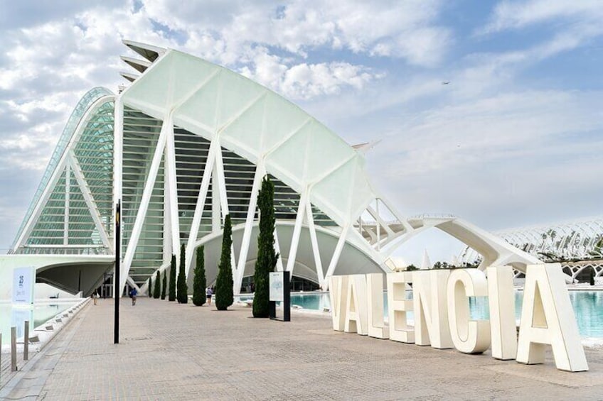 Een modern architectonisch gebouw met een gebogen dak en de tekst 'VALENCIA' duidelijk zichtbaar. 3