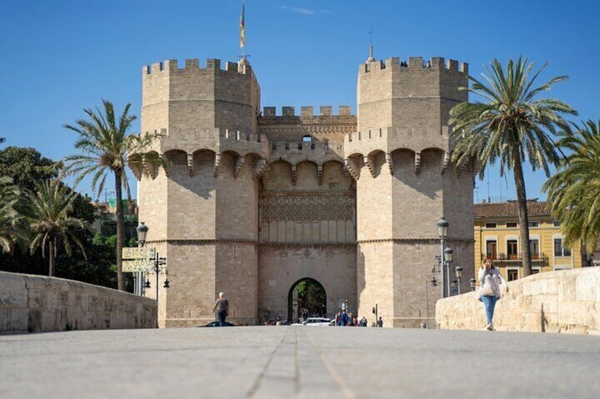 Een historische stenen poort met twee torens, palmbomen en een heldere lucht. 5
