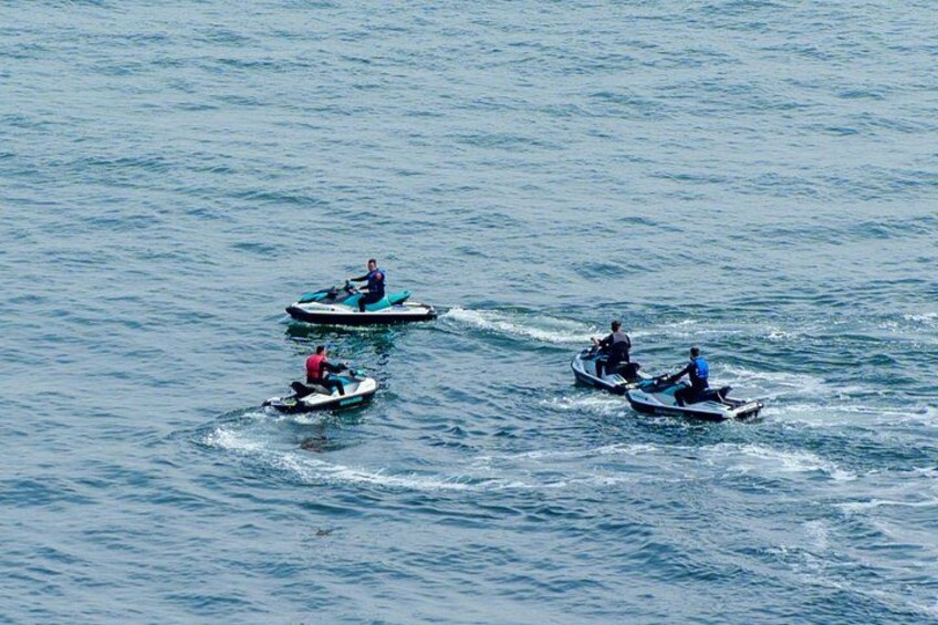 Three people on jet skis on a calm body of water. 2