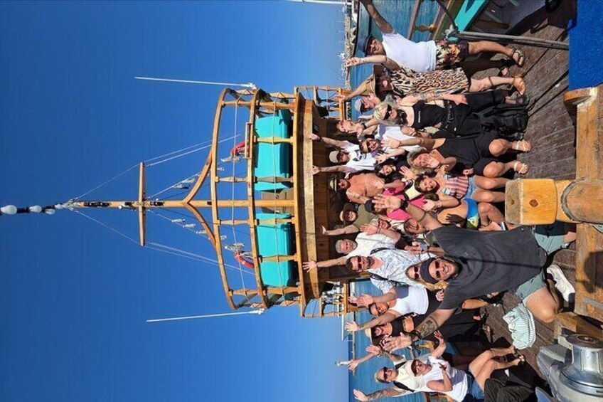 A group of people on a wooden boat with a blue canopy, docked at a pier. 2
