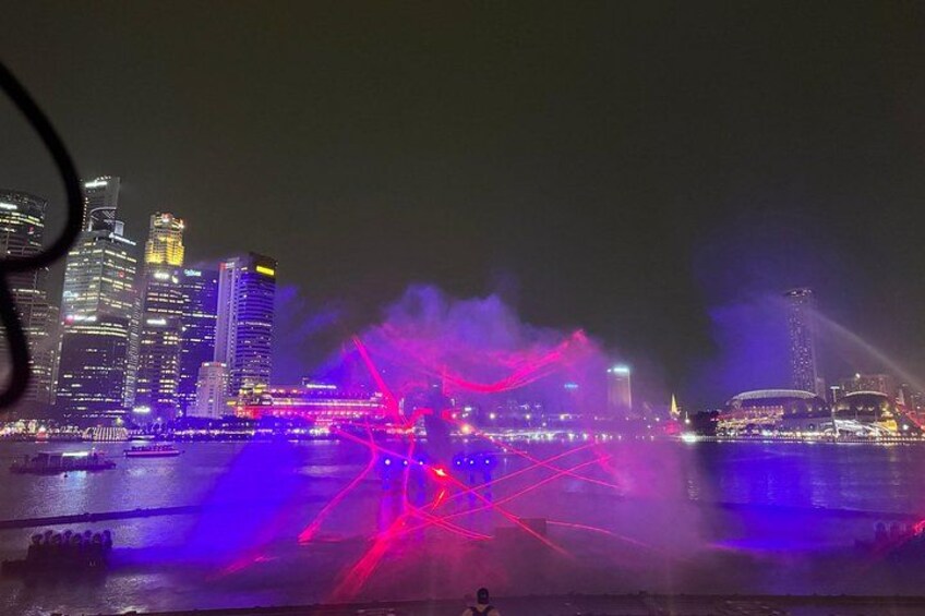 A city skyline at night with illuminated buildings and a water body reflecting lights. 2