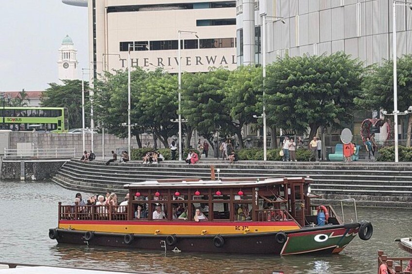 A riverboat with passengers, a building labeled 'THE RIVERWAL,' and a green bus in the background. 3