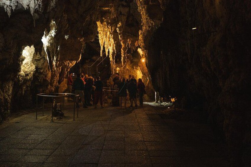 A cave with stalactites and stalagmites, people observing, and a table with a railing. 2
