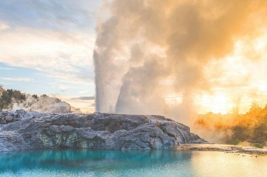 A geyser erupting, a body of water, and a forested area. 2