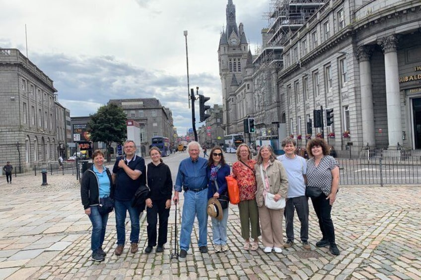 Un grupo de personas en una calle empedrada, con edificios históricos al fondo. 3