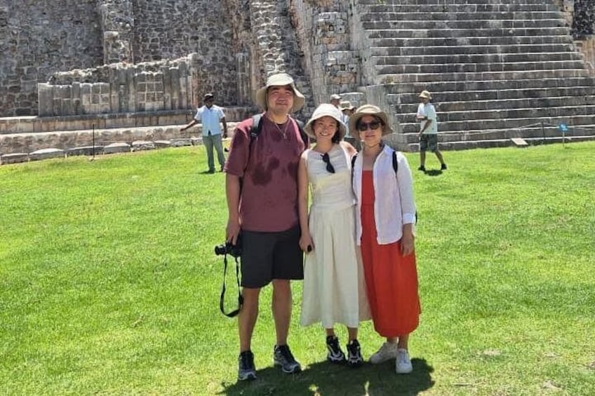 A group of people standing in front of ancient ruins with stone steps and a grassy area. 2