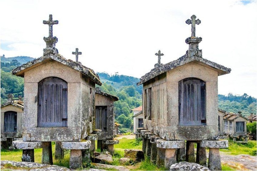 Two stone crosses with crosses on top, set against a backdrop of hills and greenery. 5