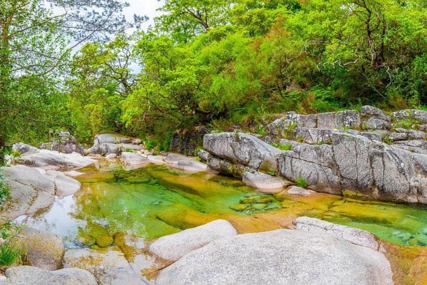 A natural landscape with a clear water body surrounded by rocks and greenery. 2
