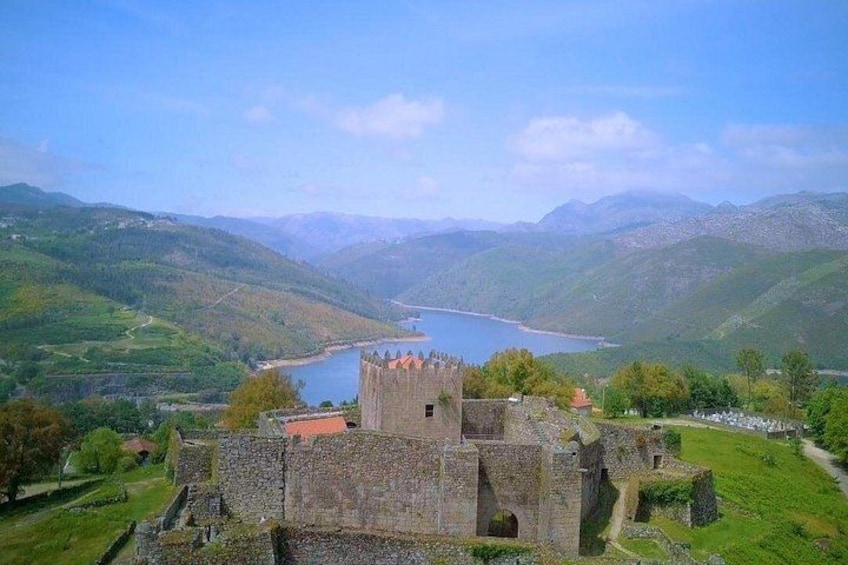 A castle surrounded by green hills and a lake. 3