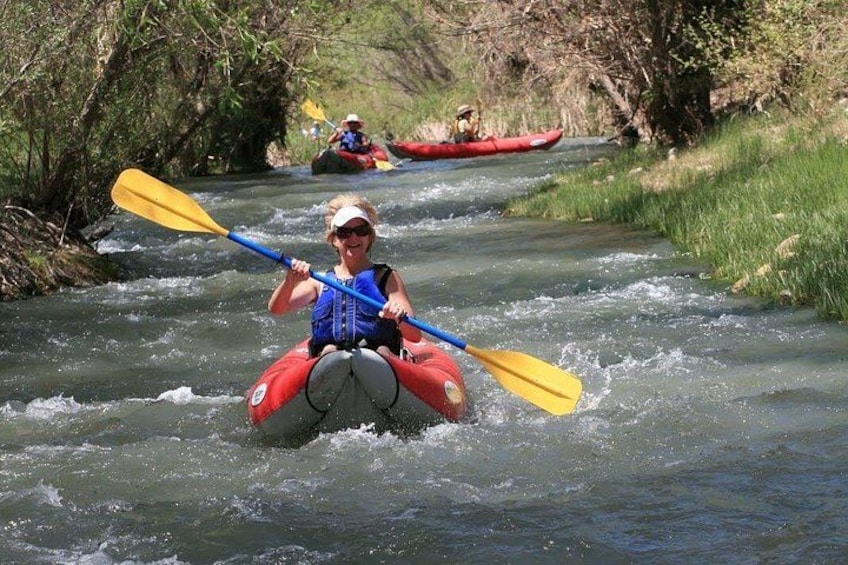 Une personne pratiquant le kayak sur une rivière, entourée de verdure. 5