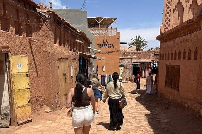 Une rue étroite bordée de bâtiments traditionnels, une enseigne indiquant « LA TERRAZZA », et des gens qui se promènent. 1