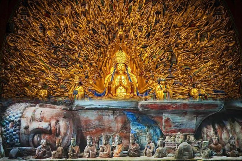 A large golden Buddha statue surrounded by smaller statues, set against a backdrop of a rocky landscape. 1