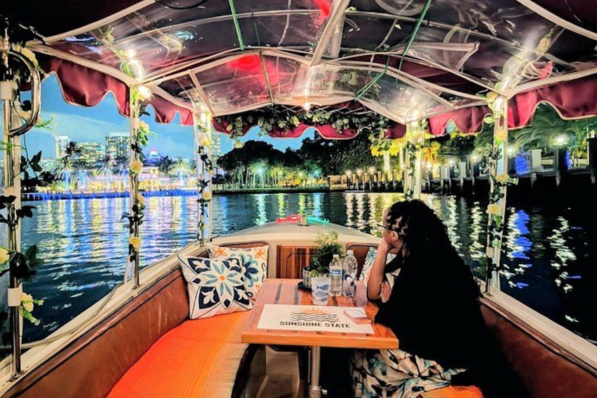 A boat with a covered dining area, a table with a menu, and a person sitting at the table. 3