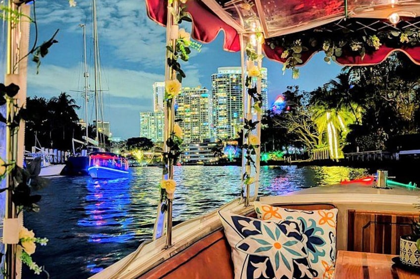A boat with a floral canopy, a city skyline in the background, and a waterfront. 4