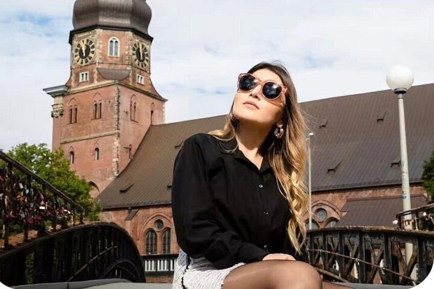 Una persona sentada en un puente, con un edificio histórico y una torre del reloj al fondo. 3