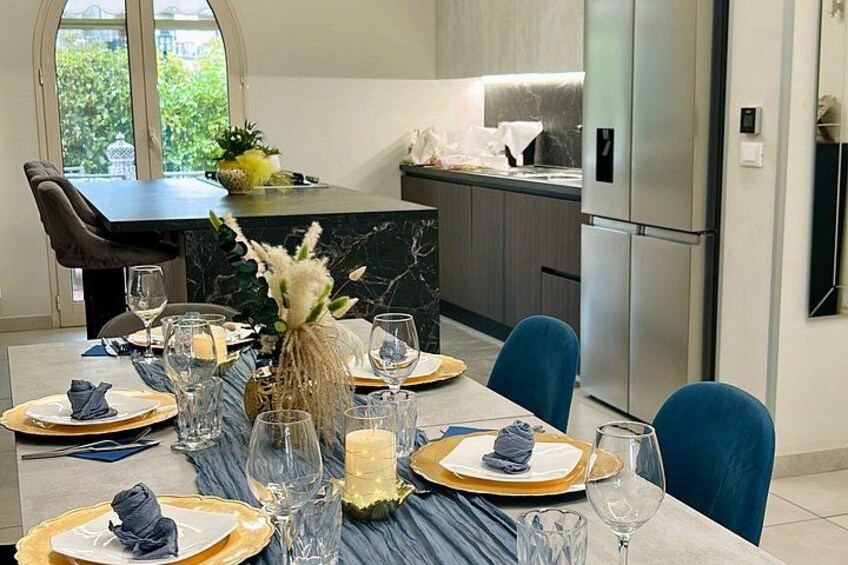 A modern kitchen with a dining table set for a meal, featuring a vase with flowers, candles, and wine glasses. 5