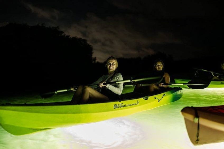 Two people in a kayak on a body of water at night. 3