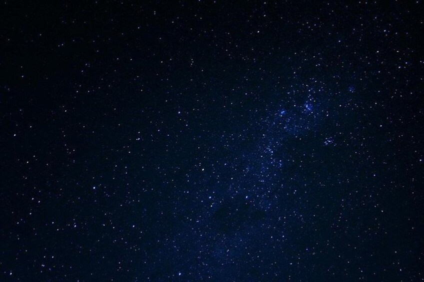A starry night sky with a dense cluster of stars and a faintly visible galaxy. 5