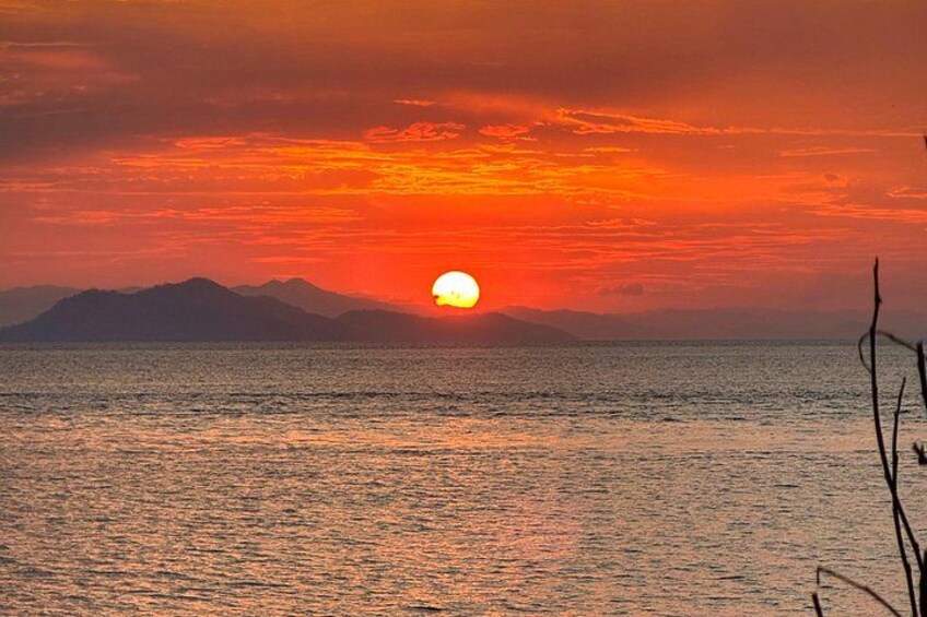 A sunset over a body of water with mountains in the background. 3