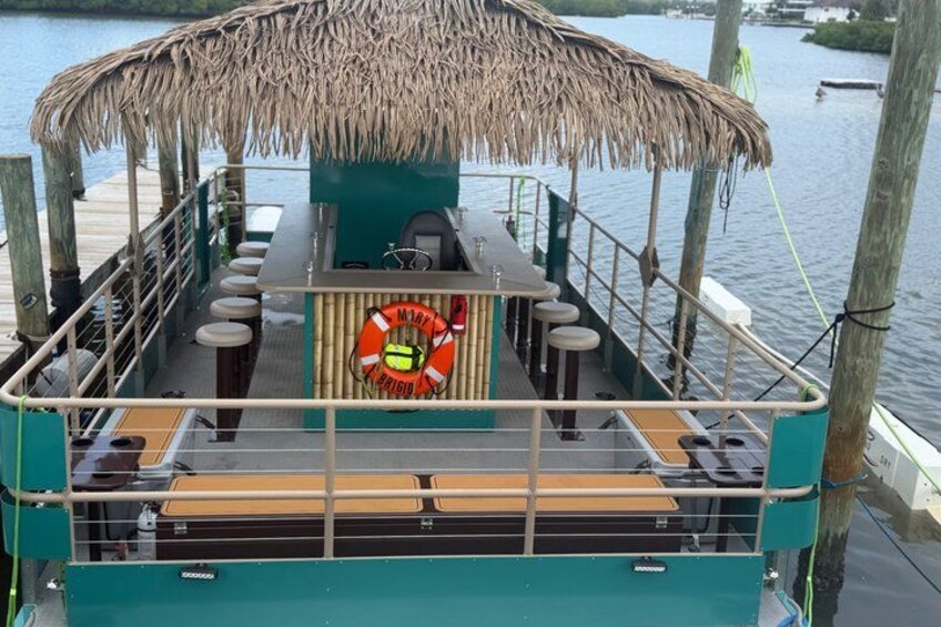 Un bote con zona de bar techada de paja, un flotador salvavidas y un área de estar. 2