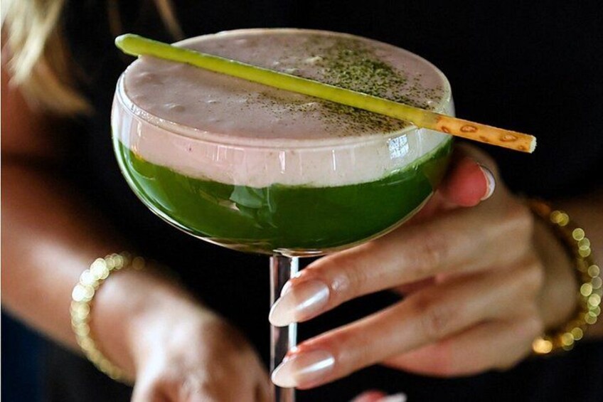 Una persona che tiene un bicchiere da cocktail con un liquido verde e una cannuccia. 4
