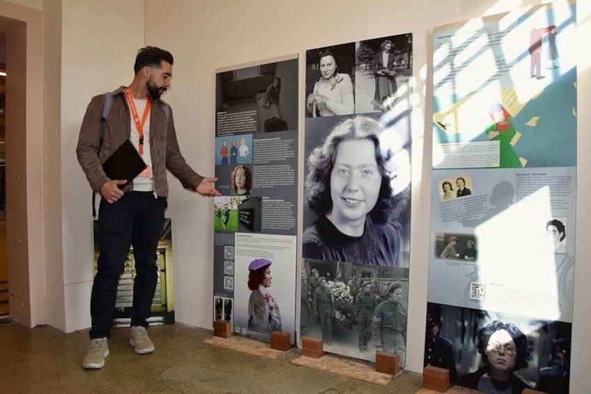 A person standing in front of a wall displaying various posters and photographs. 3