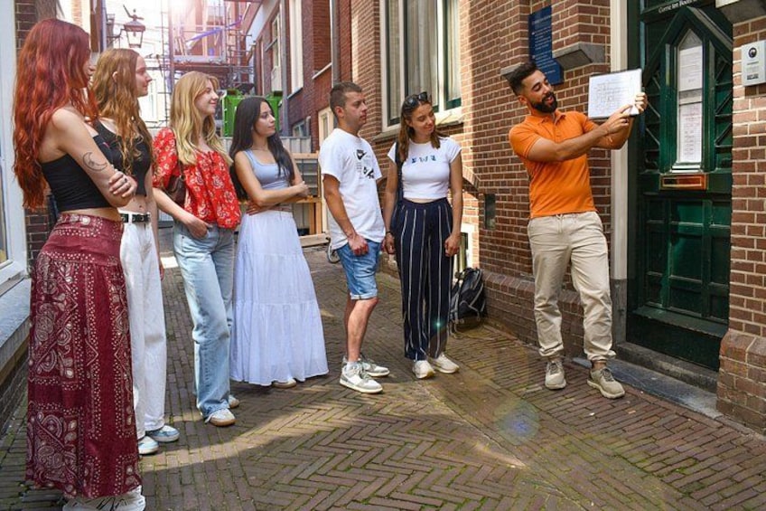 A group of people standing on a cobblestone street, a person taking a photo, and a building with a green door. 3
