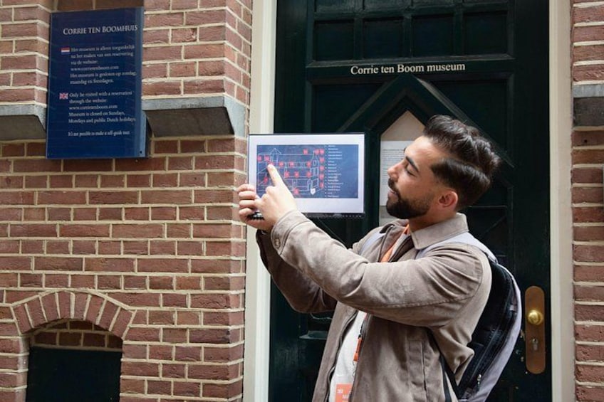 A person pointing at a display outside a building labeled 'Corrie ten Boom museum.' 2
