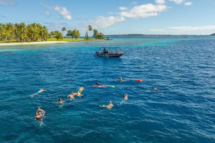 A group of people swimming in the ocean with a boat in the background. 5