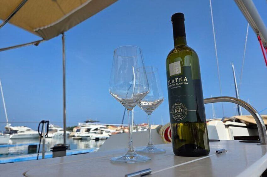 A bottle of wine and two glasses on a boat with a marina in the background. 5