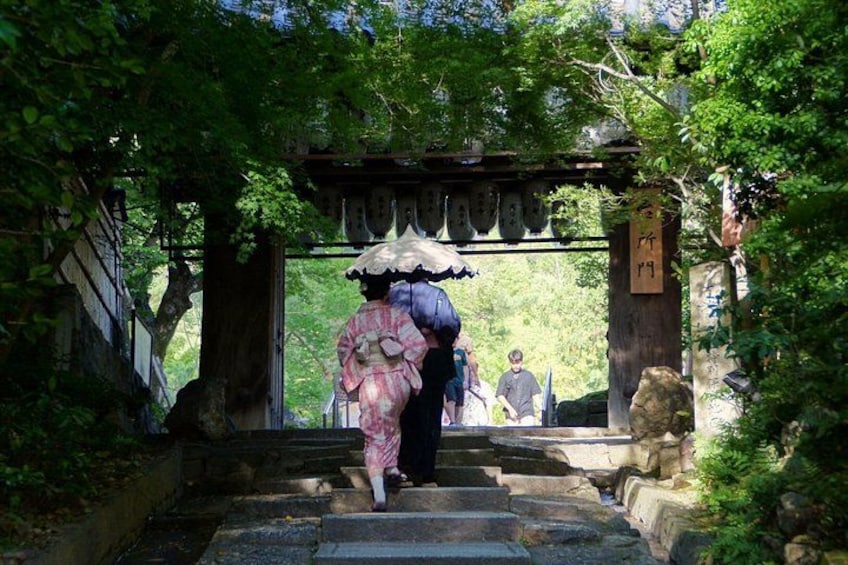 En traditionell japansk port med en person i kimono och en konformad hatt som går igenom den. 3