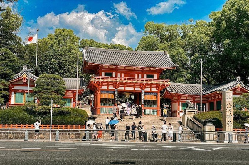 Ett traditionellt japanskt tempel med en röd port, trappsteg som leder upp till det och en flaggstång med en flagga. 4