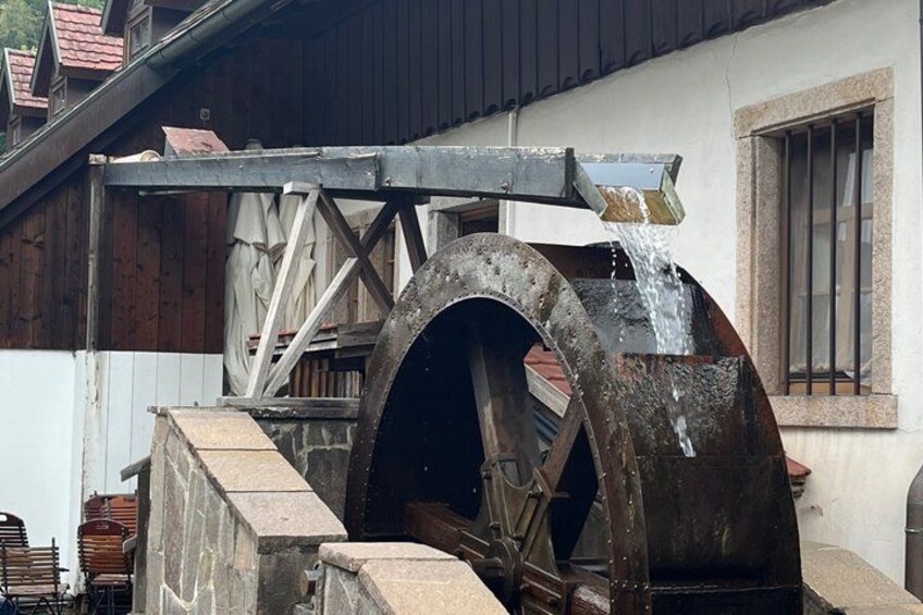 A large water wheel attached to a building with a metal structure above it. 5